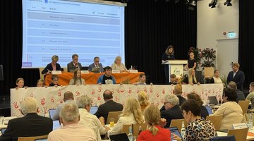 Eine Gruppe von Schülerinnen und Schülern präsentiert ein weißes Banner mit roten Handabdrücken. Im Hintergrund stehen Kreistagspolitiker, im Vordergrund sind weitere Kreistagsabgeordnete zu sehen.